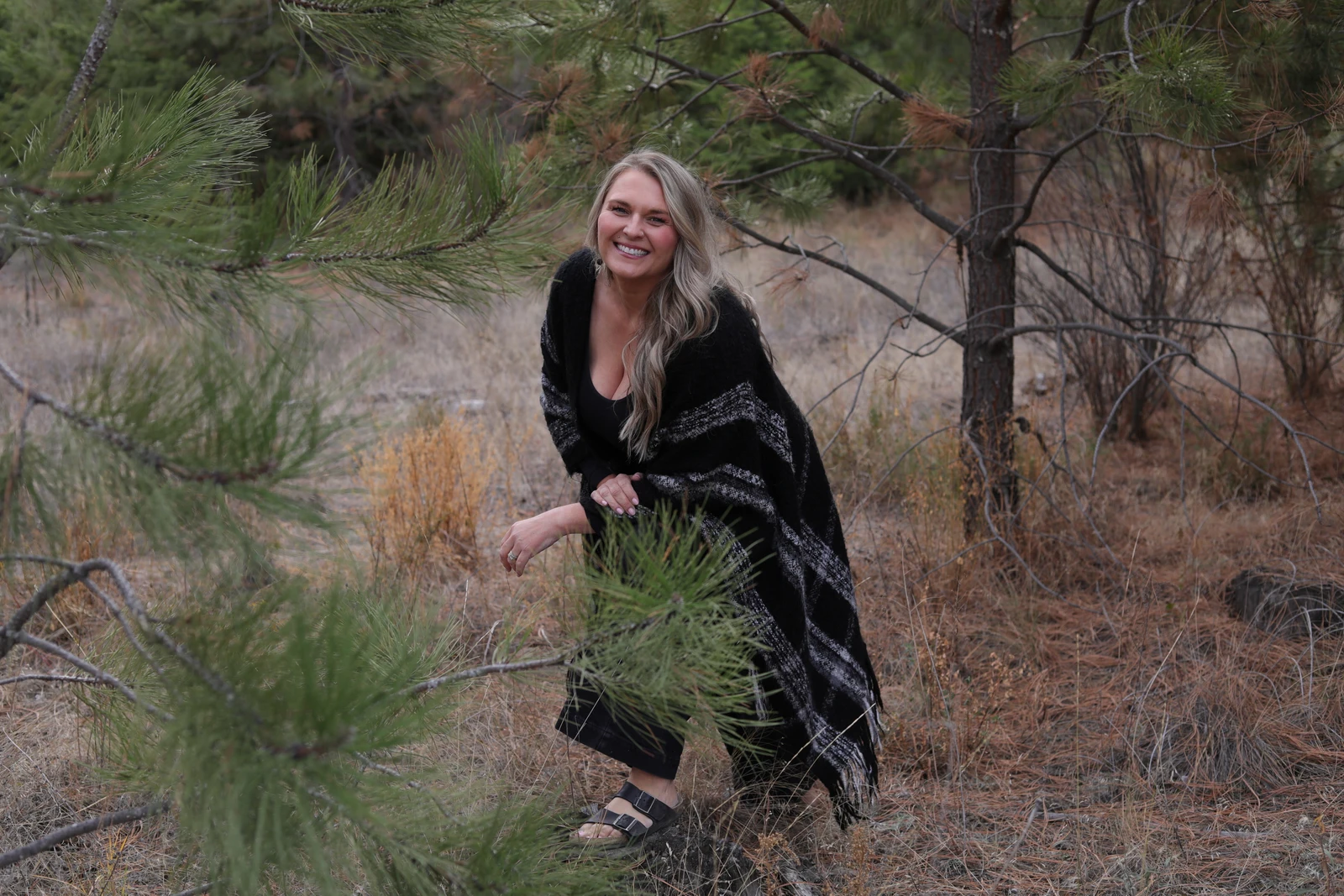 Trisha smiling among the pine trees in Kamloops